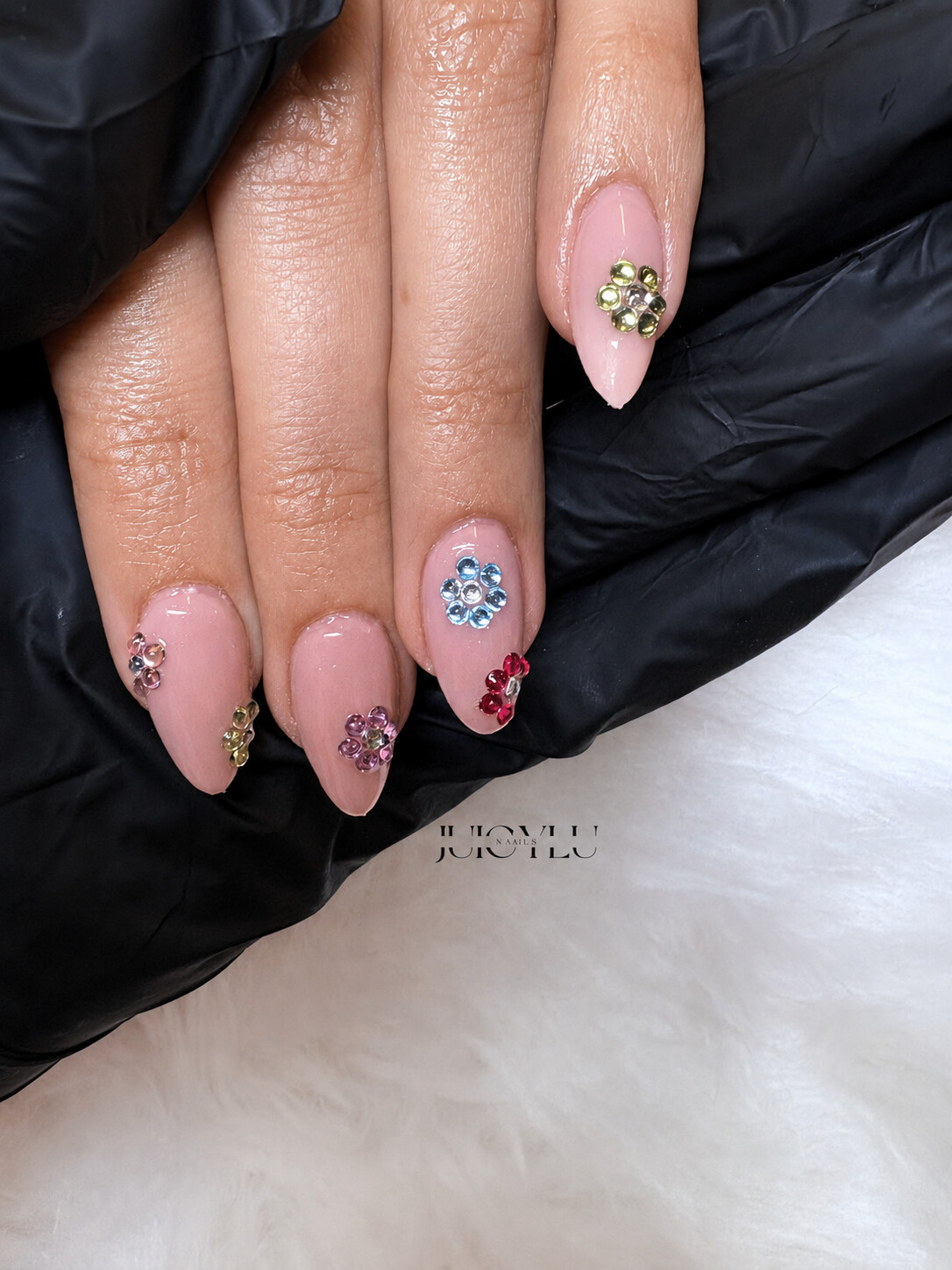 Rosafarbene Gelnägel mit bunten Kristallblumen
